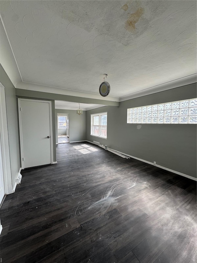 spare room featuring a chandelier, a textured ceiling, dark wood-style floors, baseboards, and visible vents