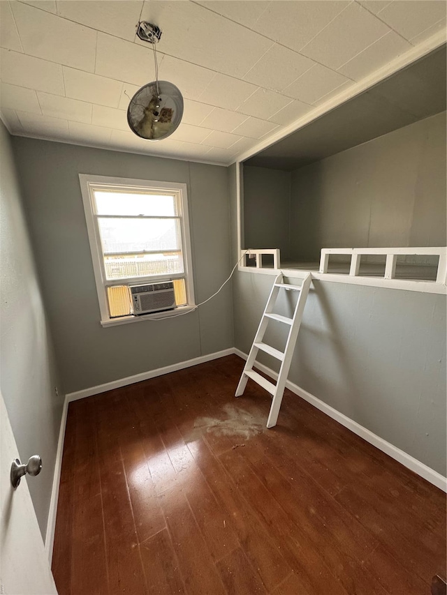 unfurnished room with baseboards, cooling unit, and hardwood / wood-style flooring