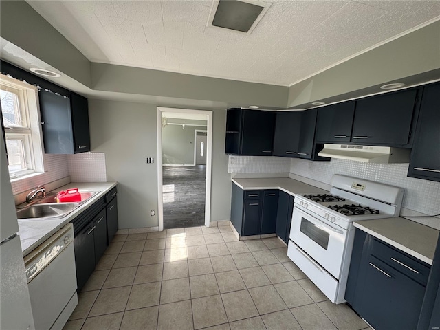kitchen featuring light countertops, ventilation hood, a sink, light tile patterned floors, and white appliances