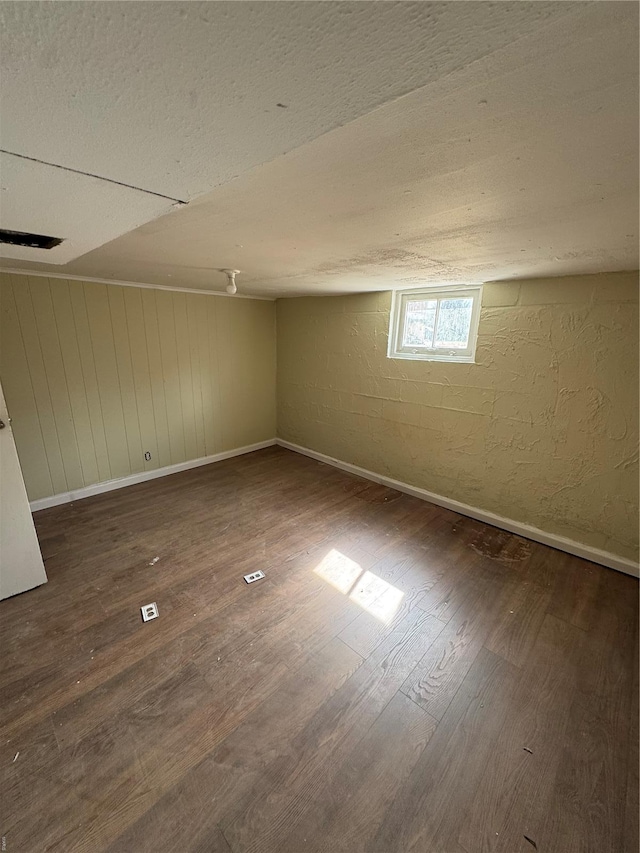 below grade area with baseboards, visible vents, and wood finished floors