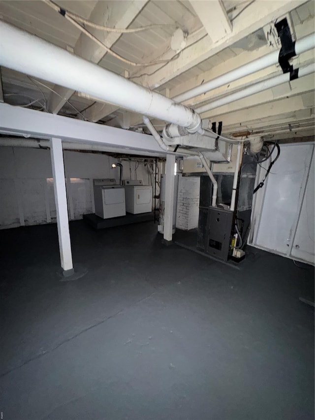 unfinished below grade area featuring washing machine and dryer, heating unit, and gas water heater