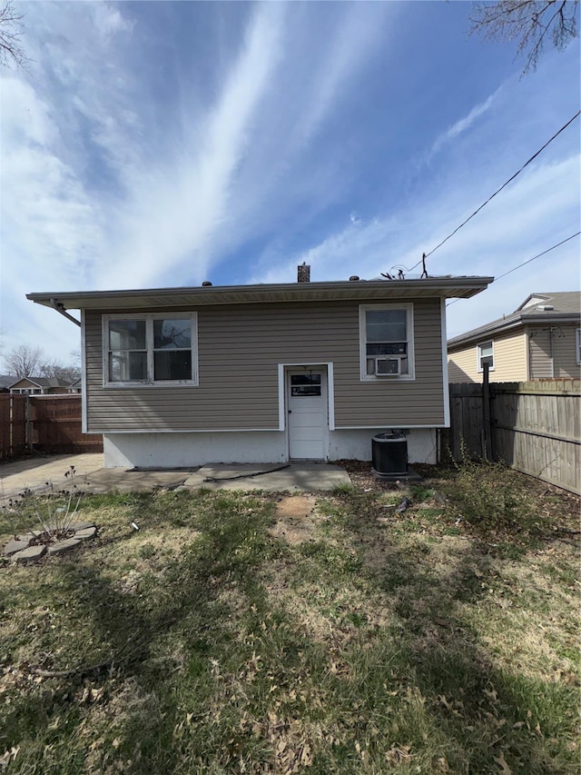 rear view of house featuring a lawn, cooling unit, and fence