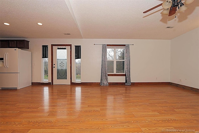 unfurnished living room featuring visible vents, light wood-style flooring, baseboards, and ceiling fan