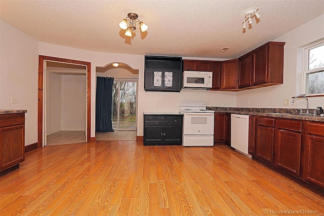 kitchen with a sink, white appliances, light wood-style floors, and a textured ceiling