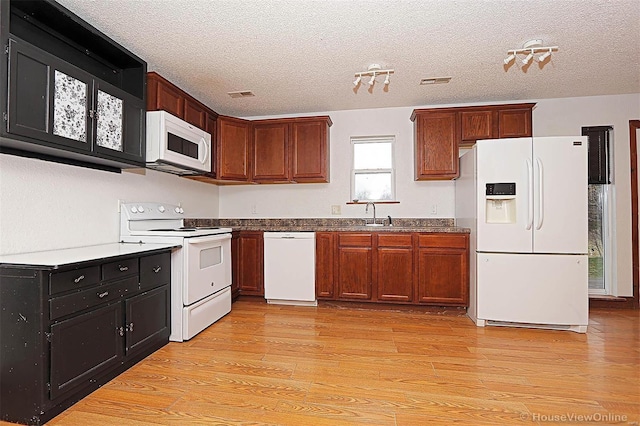 kitchen featuring a textured ceiling, white appliances, visible vents, and light wood-type flooring