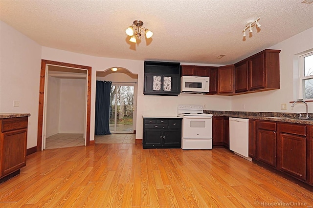 kitchen featuring light wood-style flooring, arched walkways, white appliances, a textured ceiling, and a sink