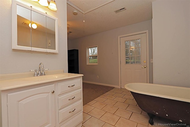 bathroom with vanity, baseboards, a freestanding tub, a textured ceiling, and tile patterned floors