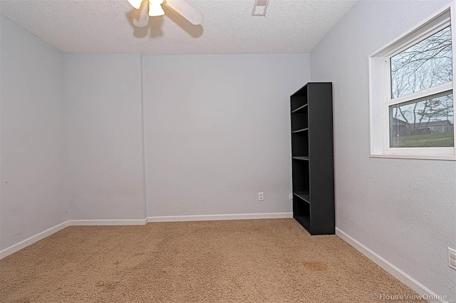 empty room with baseboards, light colored carpet, ceiling fan, and a textured ceiling