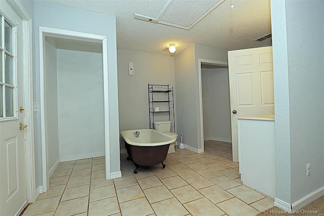 bathroom featuring tile patterned flooring, visible vents, baseboards, a freestanding bath, and a textured ceiling