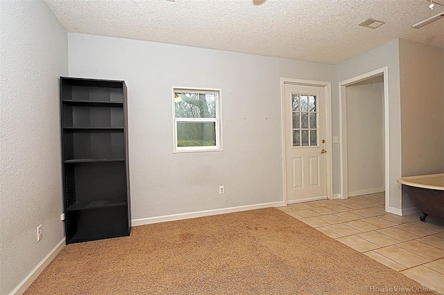 entrance foyer with light tile patterned floors, a textured ceiling, and baseboards