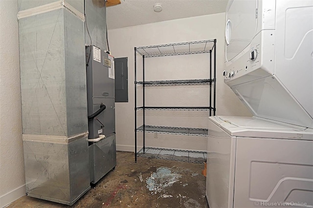 laundry area featuring stacked washer and dryer, electric panel, a textured ceiling, baseboards, and laundry area