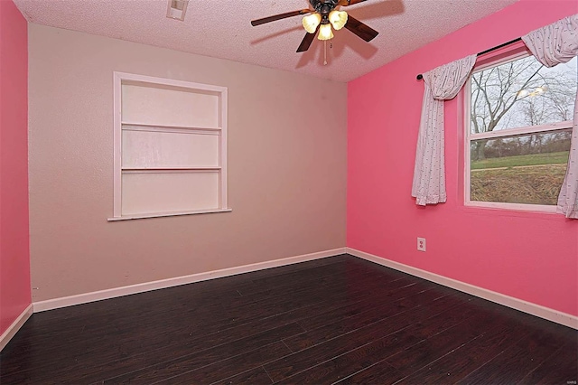 spare room featuring visible vents, a textured ceiling, dark wood finished floors, baseboards, and ceiling fan