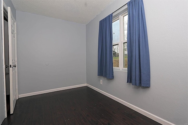 spare room featuring baseboards, a healthy amount of sunlight, and dark wood-style flooring