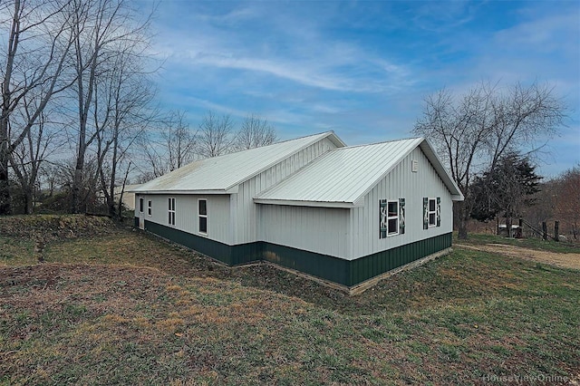 view of side of property with metal roof and a lawn