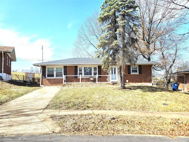 ranch-style house featuring brick siding, a porch, concrete driveway, and a front yard