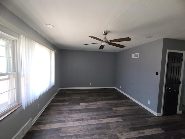spare room with visible vents, baseboards, dark wood-type flooring, and a ceiling fan