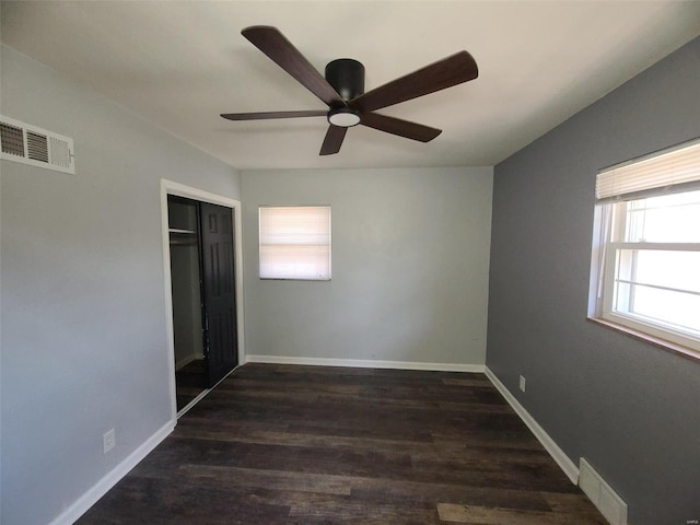 unfurnished bedroom with wood finished floors, baseboards, and visible vents