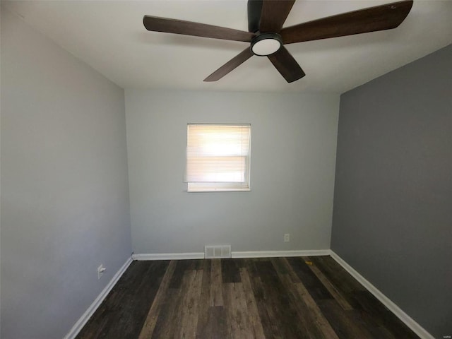 spare room with dark wood finished floors, visible vents, ceiling fan, and baseboards