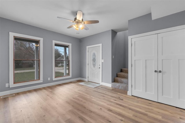 foyer entrance featuring visible vents, ceiling fan, baseboards, stairs, and light wood-style floors