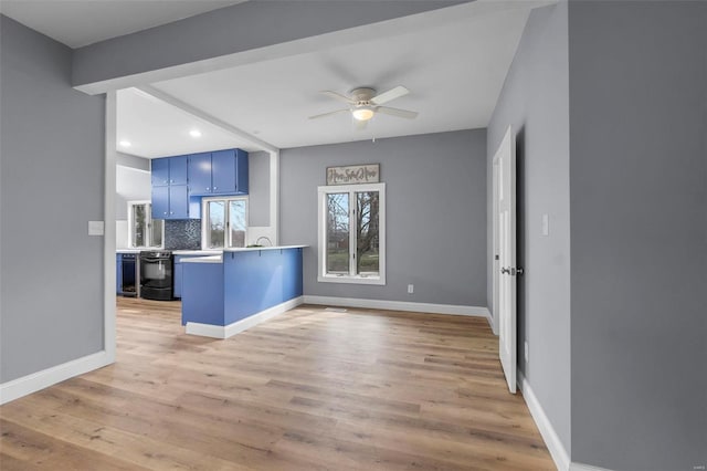 kitchen with a ceiling fan, a peninsula, decorative backsplash, light wood-style floors, and blue cabinets