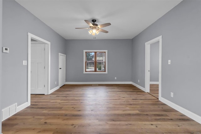 empty room with visible vents, baseboards, ceiling fan, and wood finished floors