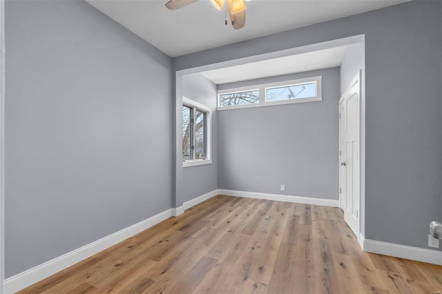 spare room with baseboards, ceiling fan, and light wood finished floors