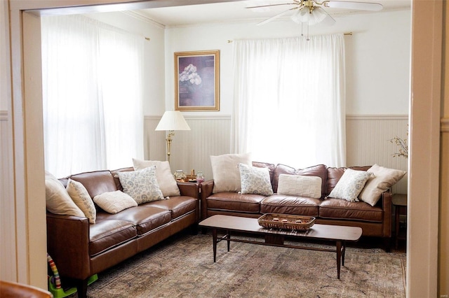 living area with wainscoting, ceiling fan, and ornamental molding