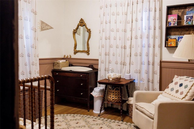 bedroom featuring a wainscoted wall and wood finished floors