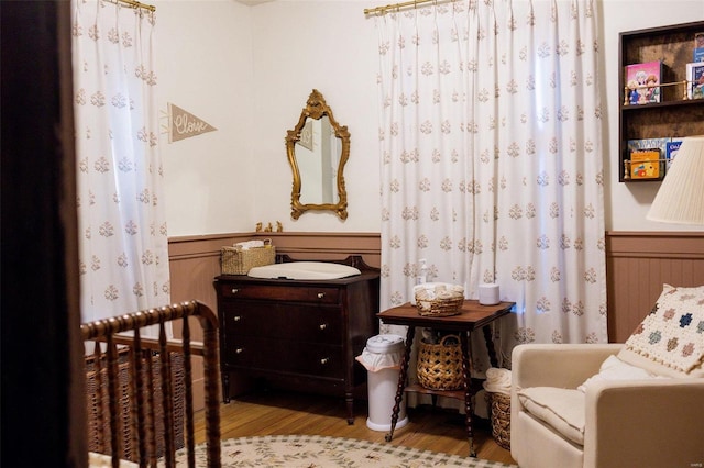 bedroom featuring wood finished floors and wainscoting