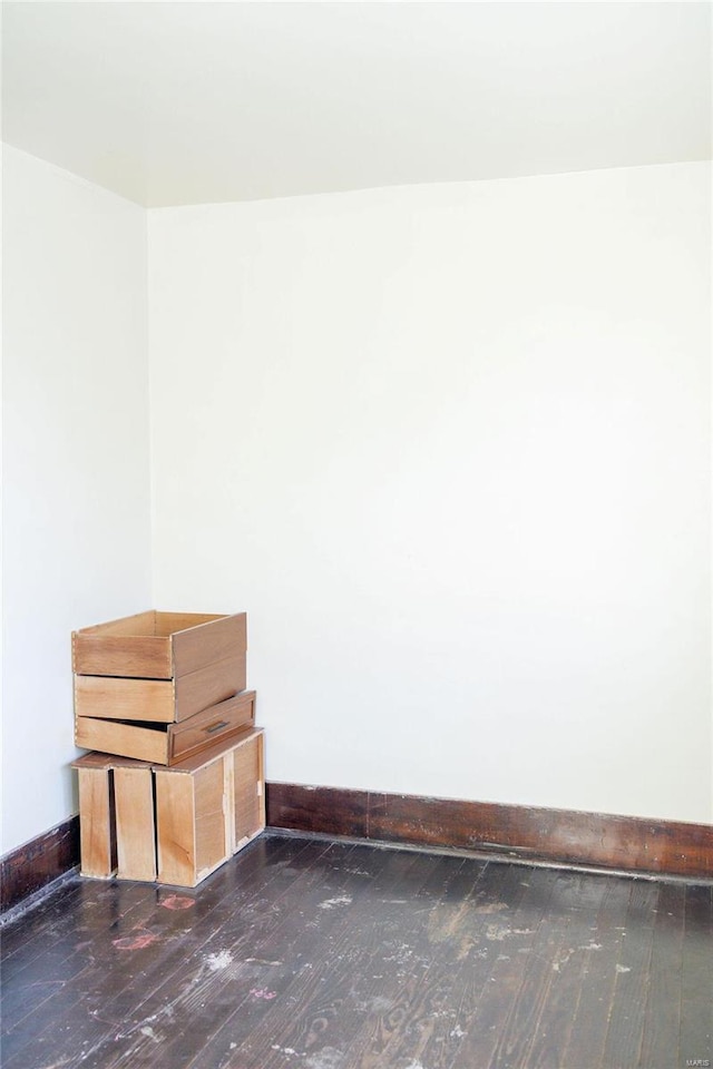 unfurnished room with baseboards and wood-type flooring