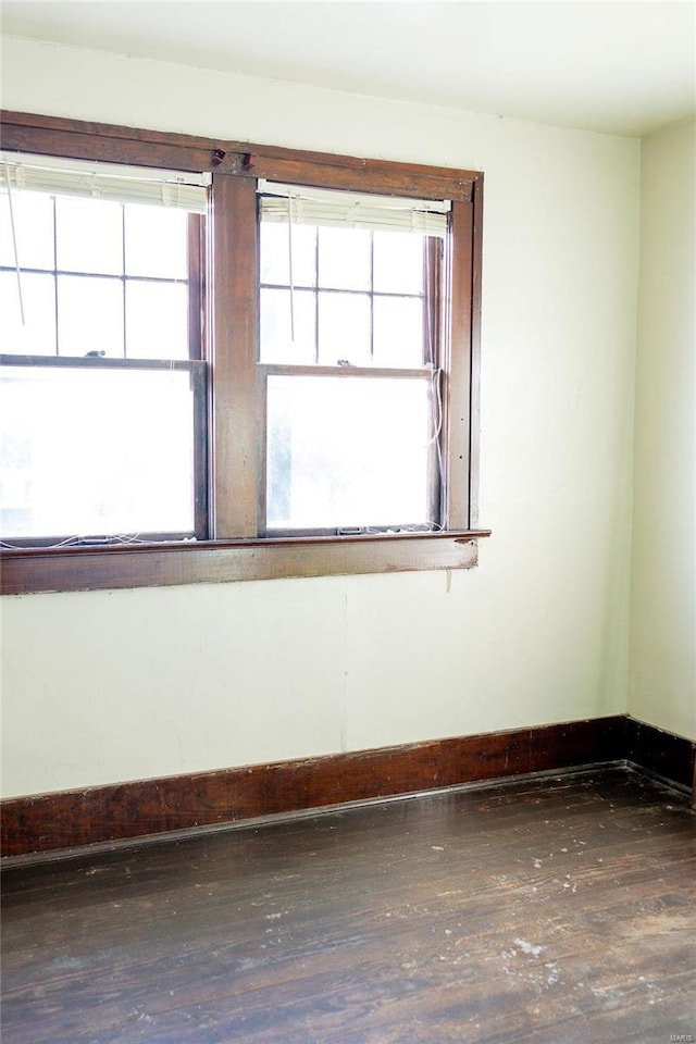 spare room featuring baseboards and wood-type flooring