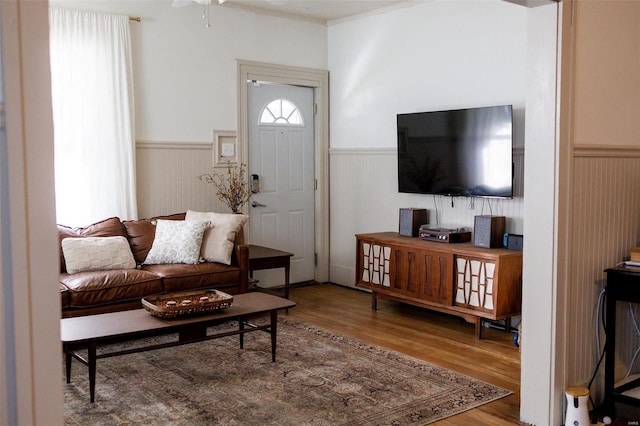 living area featuring ceiling fan, wood finished floors, and wainscoting