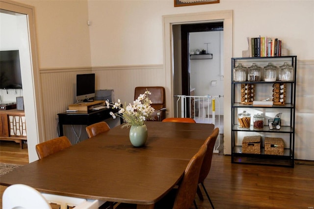 dining space featuring wood finished floors and wainscoting