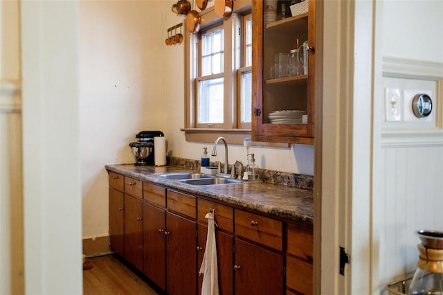 kitchen featuring a sink, dark countertops, wood finished floors, and brown cabinetry