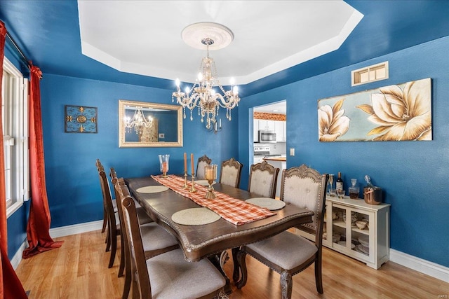 dining room featuring a tray ceiling, baseboards, a notable chandelier, and visible vents