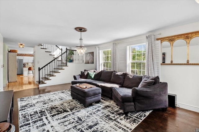 living room with baseboards, wood finished floors, a chandelier, and stairway