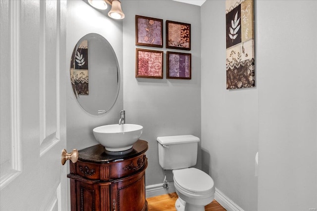 half bath featuring toilet, baseboards, and vanity