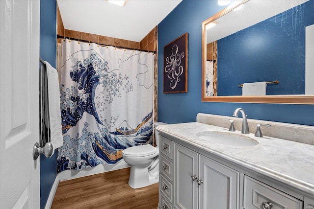 bathroom with vanity, wood finished floors, toilet, and curtained shower