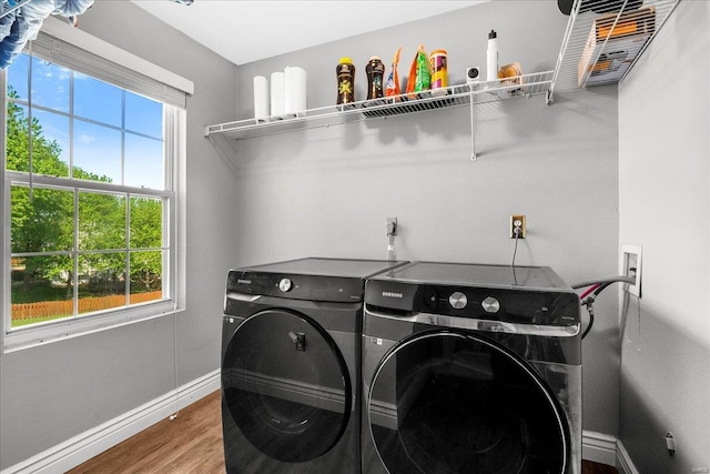 laundry room with laundry area, baseboards, washing machine and dryer, and wood finished floors