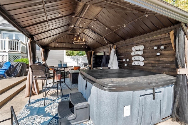 view of patio with fence, outdoor dining space, a gazebo, a hot tub, and a grill
