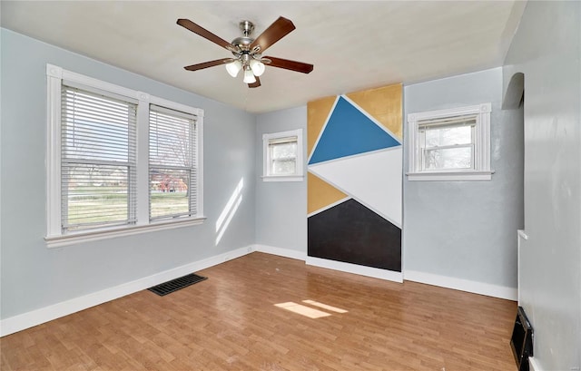 additional living space featuring wood finished floors, plenty of natural light, baseboards, visible vents, and ceiling fan