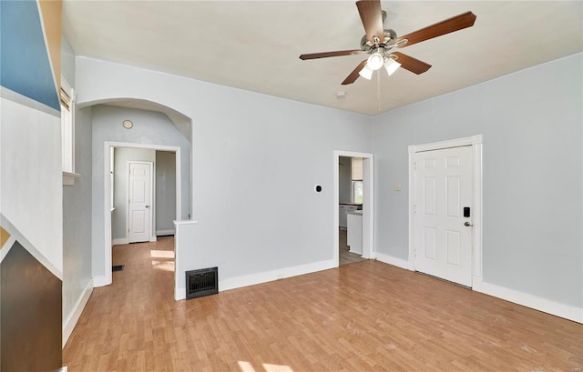 spare room with arched walkways, ceiling fan, visible vents, and light wood-style floors