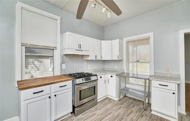 kitchen featuring wood counters, ceiling fan, under cabinet range hood, white cabinetry, and stainless steel gas range oven