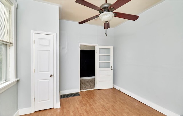 spare room featuring baseboards, ceiling fan, visible vents, and light wood finished floors