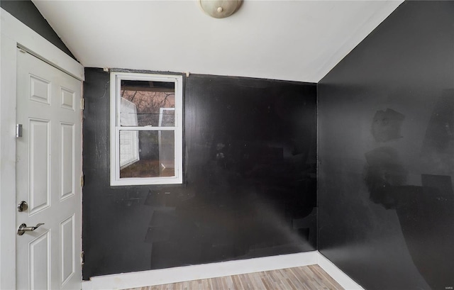 interior space with baseboards, vaulted ceiling, and wood finished floors
