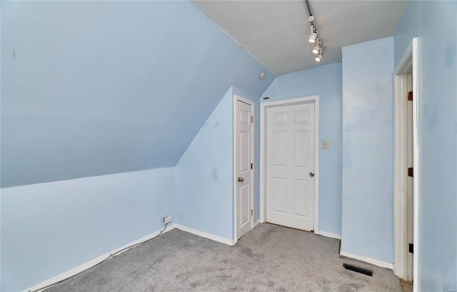 additional living space featuring baseboards, visible vents, vaulted ceiling, and carpet