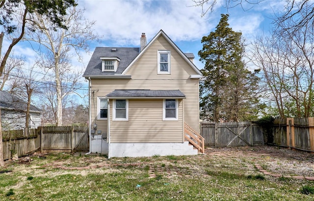 rear view of house with a chimney, a fenced backyard, and a yard