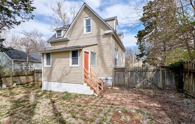 rear view of house with a fenced backyard and entry steps