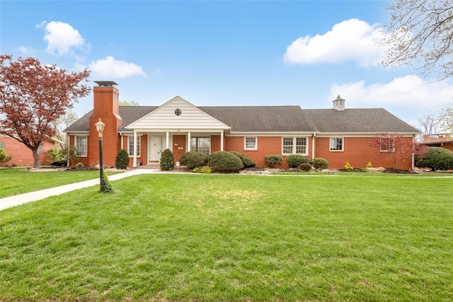 neoclassical / greek revival house featuring a front yard, roof with shingles, brick siding, and a chimney
