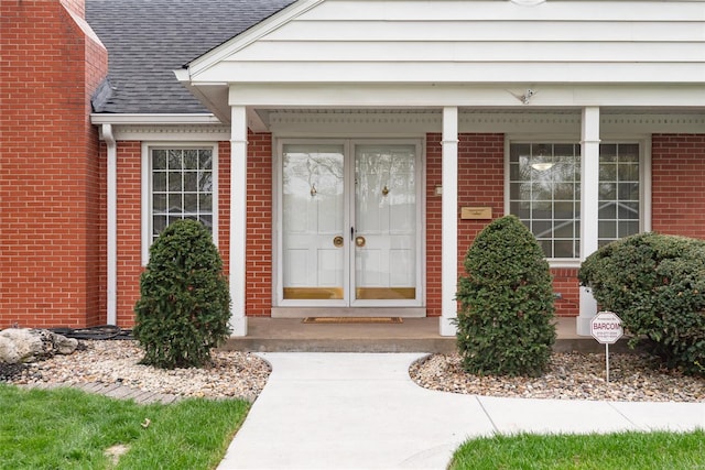property entrance with a shingled roof and brick siding